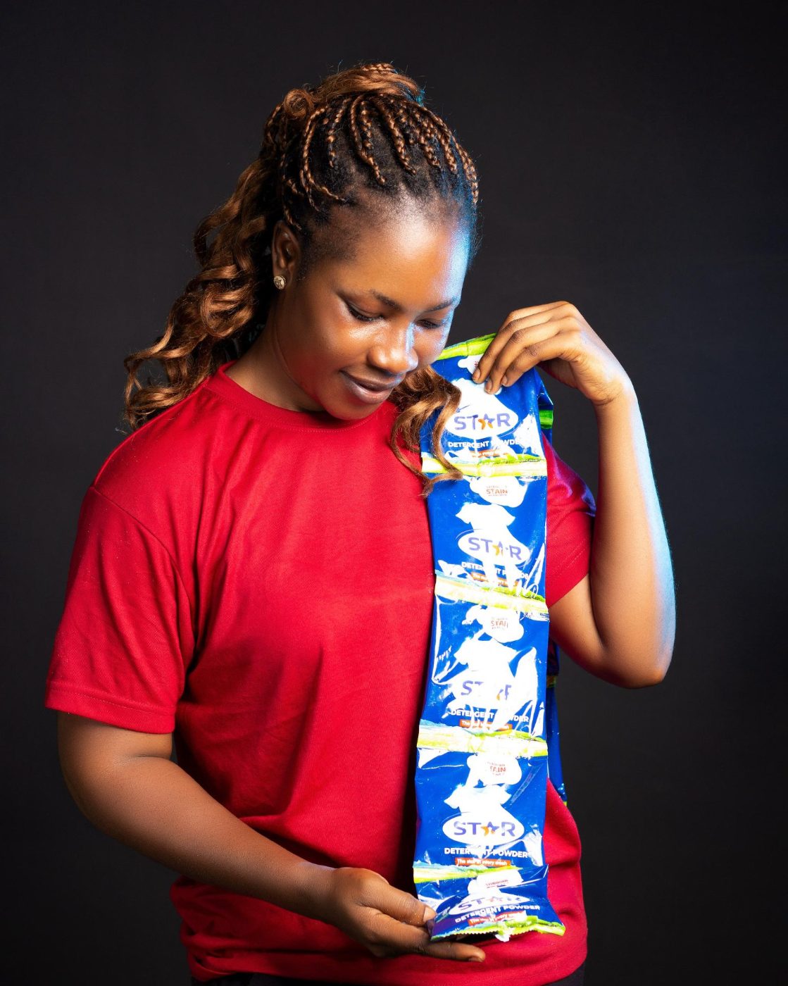 A woman proudly holding a strip of STAR detergent powder sachets
